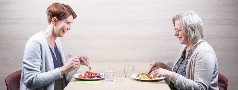 Kaksi naista syö lounasta pöydän ääressä.