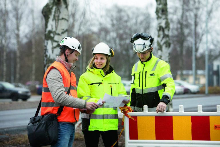 Kuvassa kolme työntekijää, joilla heijastavat työvaatteet päällä.