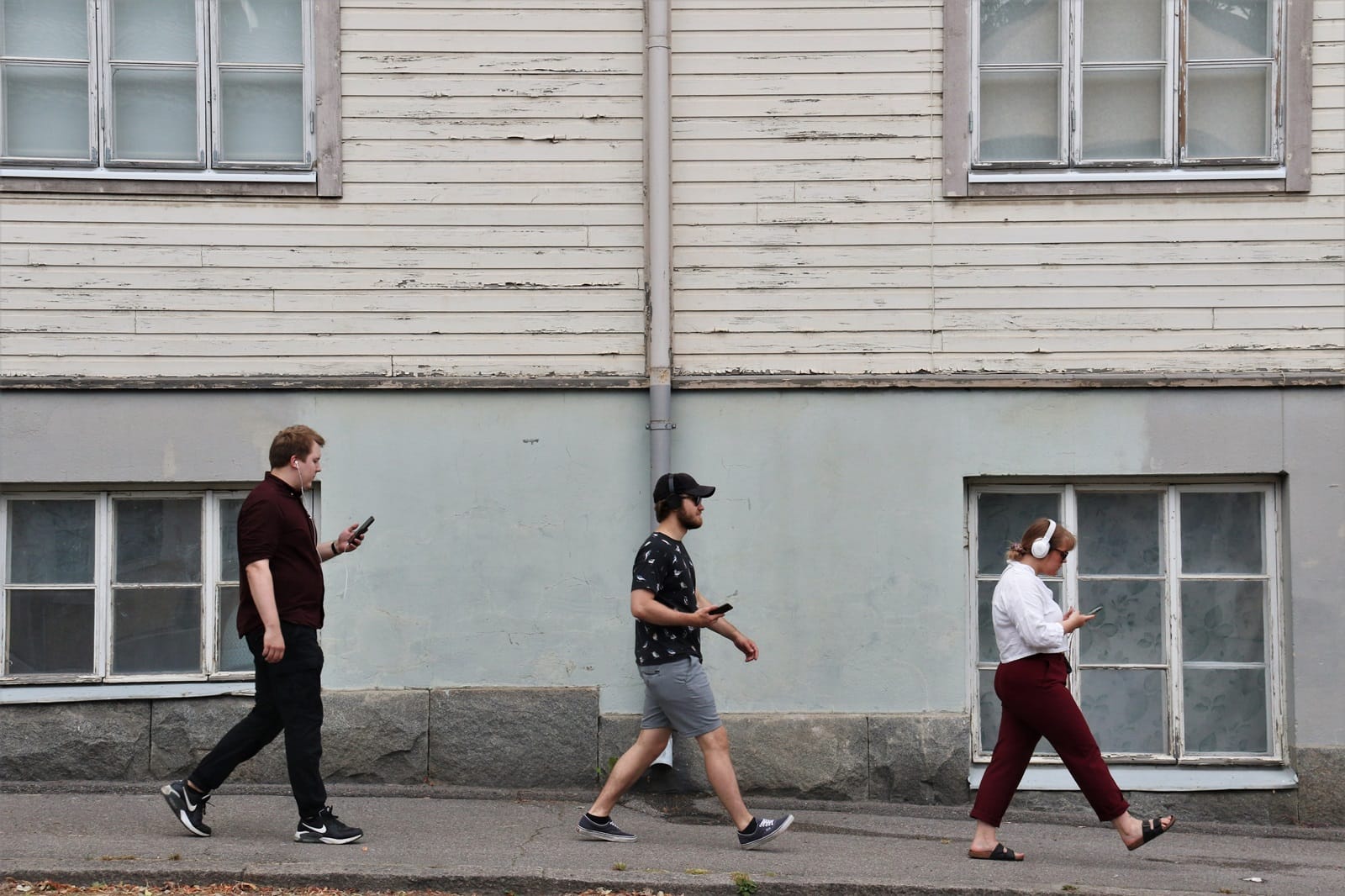 Valokuva. Nuoria henkilöitä kävelemässä kaupunkimaisessa ympäristössä. Kolme henkilöä.