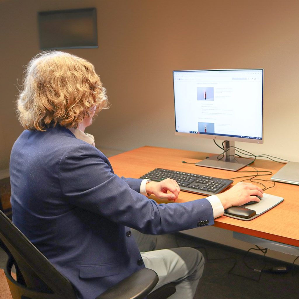 Mies opiskelee verkkokurssia tietokoneella toimistossa.