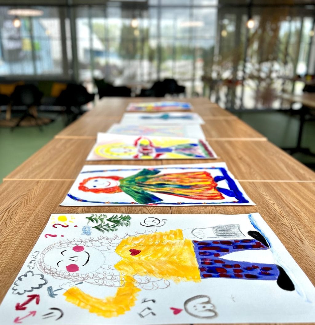 Värikkäitä maalauksia rivissä pöydällä.