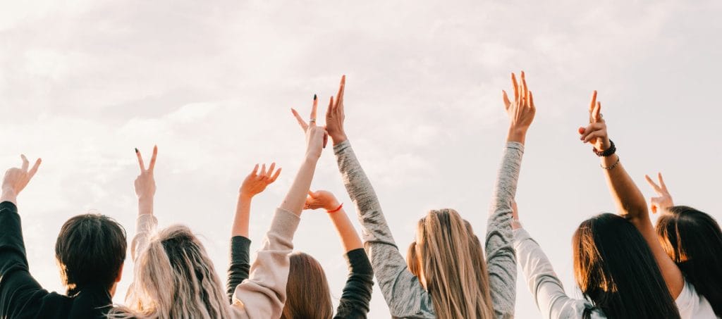 Youth fun. Spiritual freedom joy. Teen guys girls enjoying sunset with hands up in air.