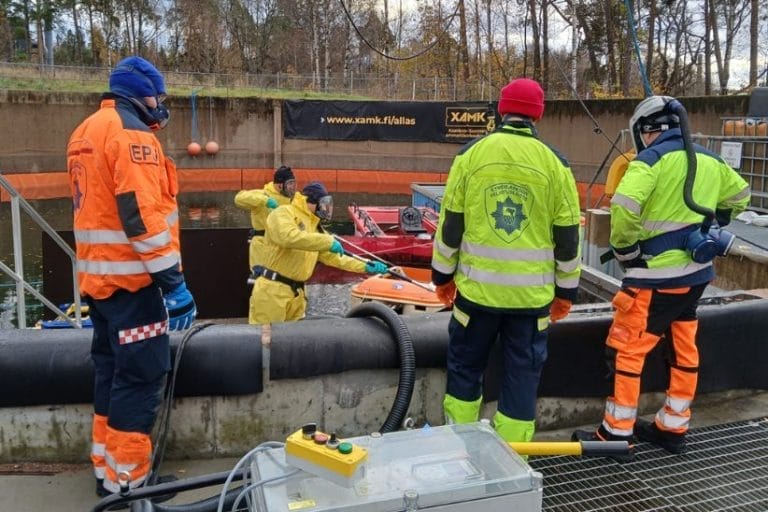 Pelastuslaitoksen ja Xamkin henkilöstö yhdessä käsittelemässä öljyntorjuntakalustoa pihalla.